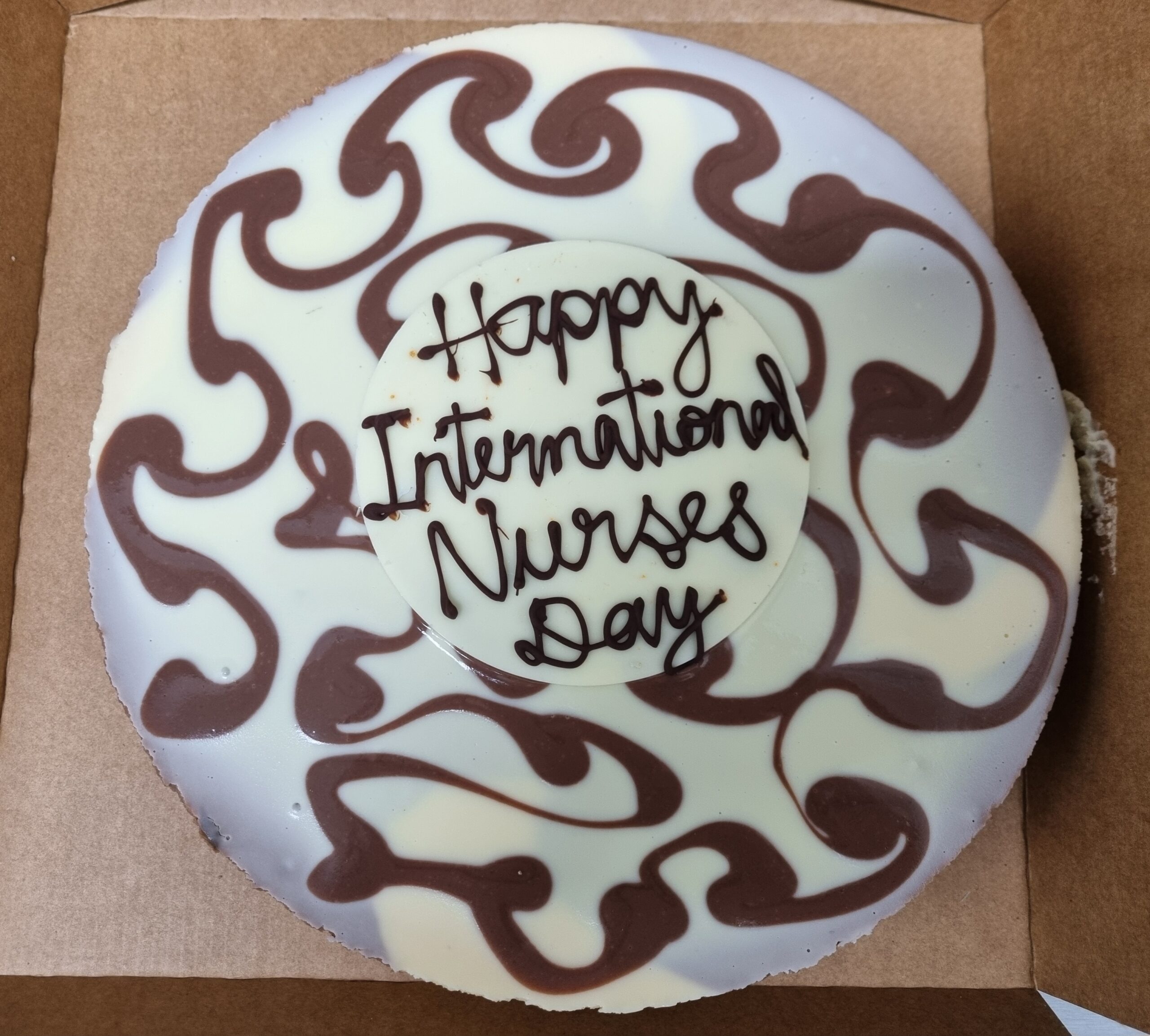 Birds-eye-view of a chocolate and vanilla marble cheesecake with the plaque: Happy International Nurses Day